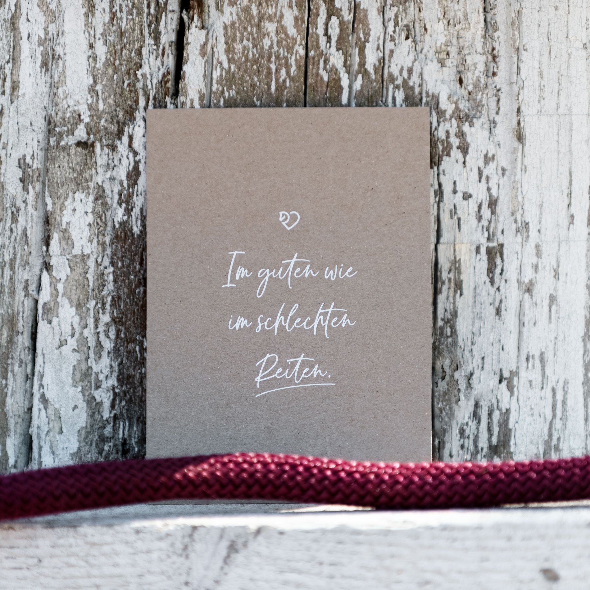 Kraftpapier Postkarte mit weißer Schrift vor hellem Holz